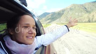 微笑着年轻的黑发女人在一辆车里玩风，开车经过美丽的山脉。 3840x2160